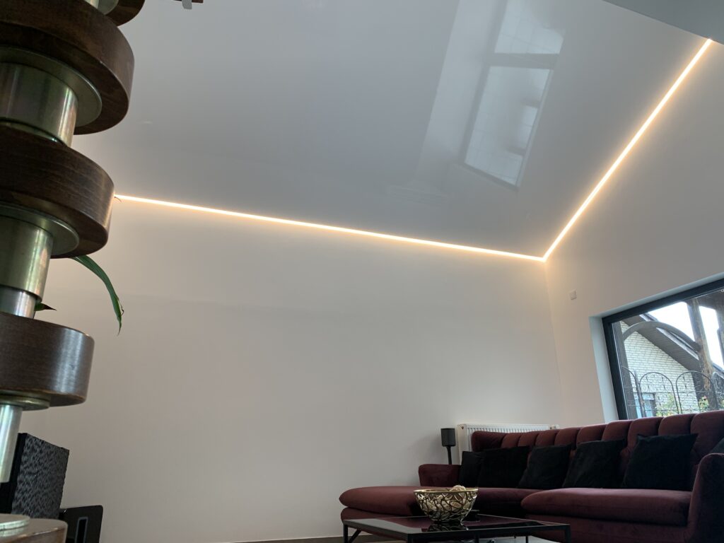 Wohnzimmer_Lackspanndecke_weiß Weiße Lackspanndecke mit umlaufender LED-Beleuchtung in einem Wohnzimmer.
