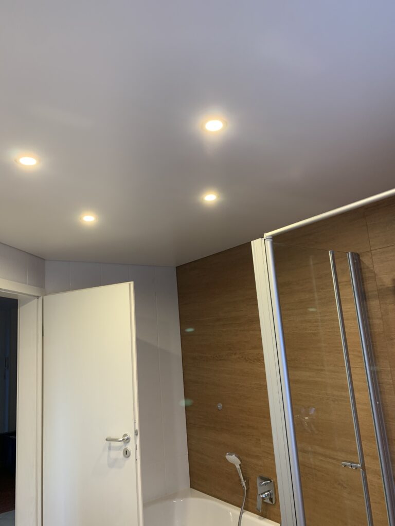 Matte Spanndecke in weiß mit vier Einbaustrahlern in einem Bad.