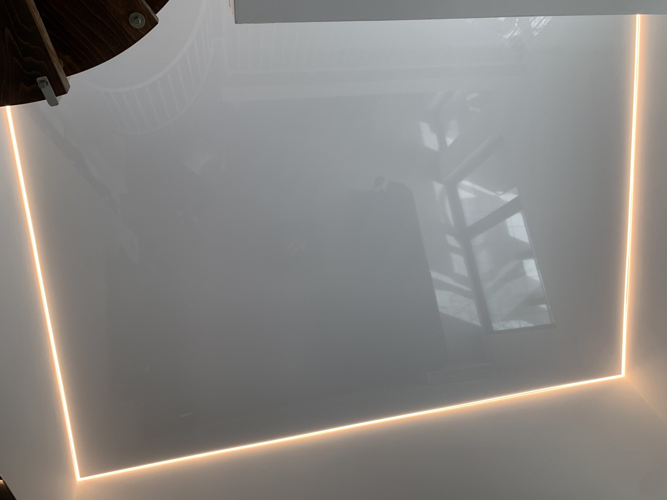 Weiße Lackspanndecke mit umlaufender LED-Beleuchtung in einem Wohnzimmer.