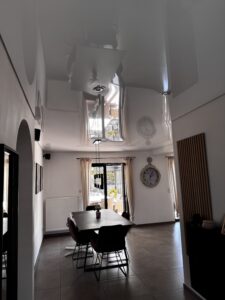 Weiße Lackspanndecke im Esszimmer und Eingangsbereich mit Deckenleuchte und Einbaustrahler.