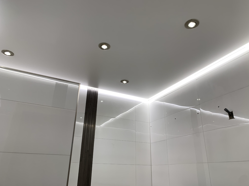 1_Lackspanndecke_LED_Einbaustrahler_LED_Beleuchtung_Bad_Rüsselsheim Weiße Lackspanndecke mit neutralweißer LED-Beleuchtung in der Schattenfuge und LED-Einbaustrahler in einem Bad in Bauschheim