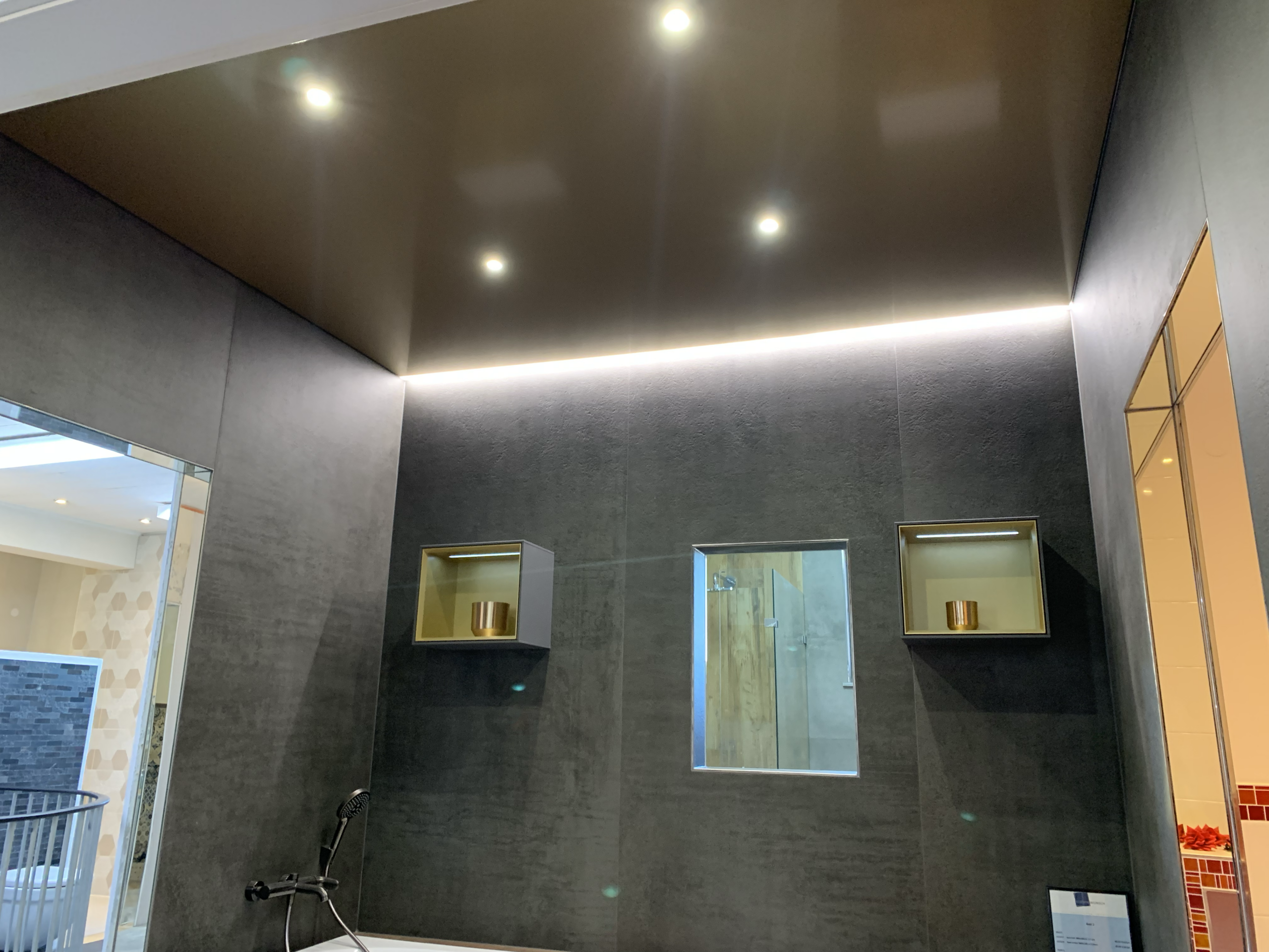 Spanndecke in Gold Metallic mit warmweißer LED-Beleuchtung in der Schattenfuge und LED Einbaustrahler in einer Fliesenausstellung in Darmstadt
