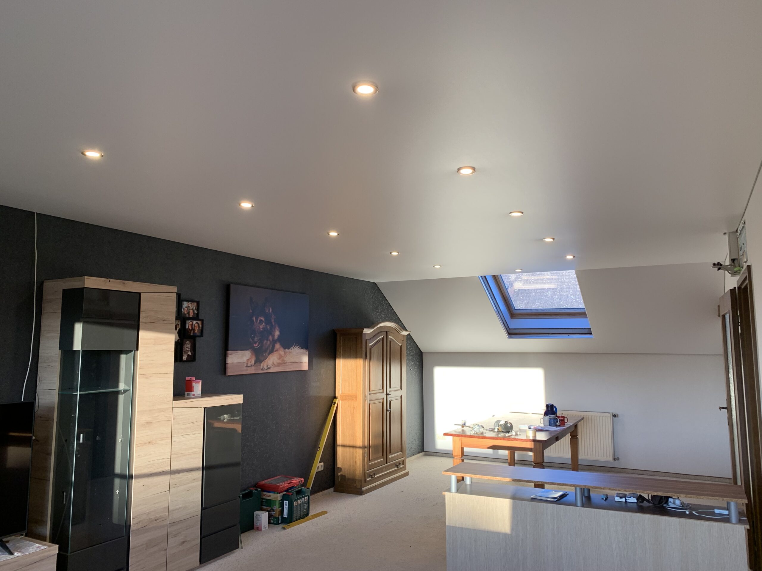 Weiße Satin Spanndecke mit LED-Einbaustrahler in einem Ess- und Wohnzimmer mit Dachschräge in Trebur