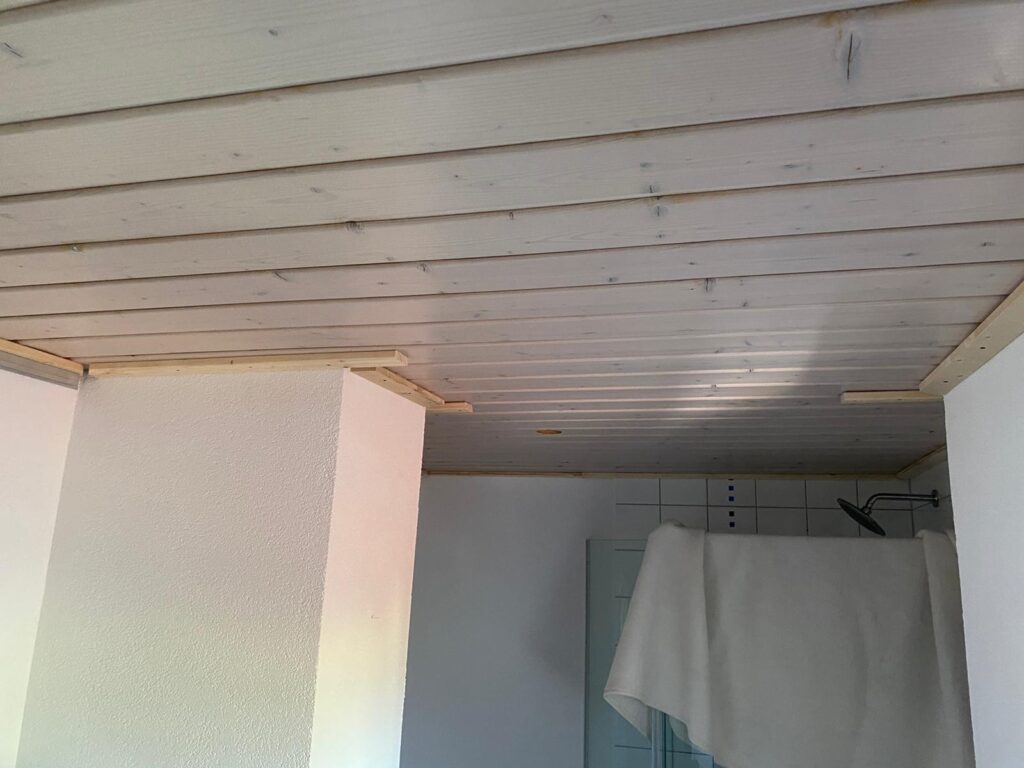 2_Vorher_Bad_Deckenpaneele Decke vor Montage eine weißen Lackpanndecke mit neutralweißer LED-Beleuchtung in der Schattenfuge in einem Bad