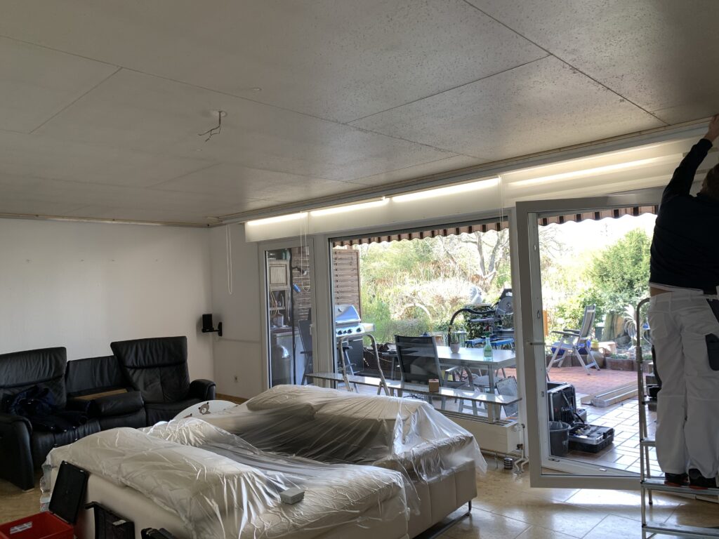 2_Vorher_Wohnzimmer_Deckenplatten Decke vor Montage eine weißen Lackspanndecke mit RGBW LED-Beleuchtung in der Schattenfuge in einem Wohnzimmer