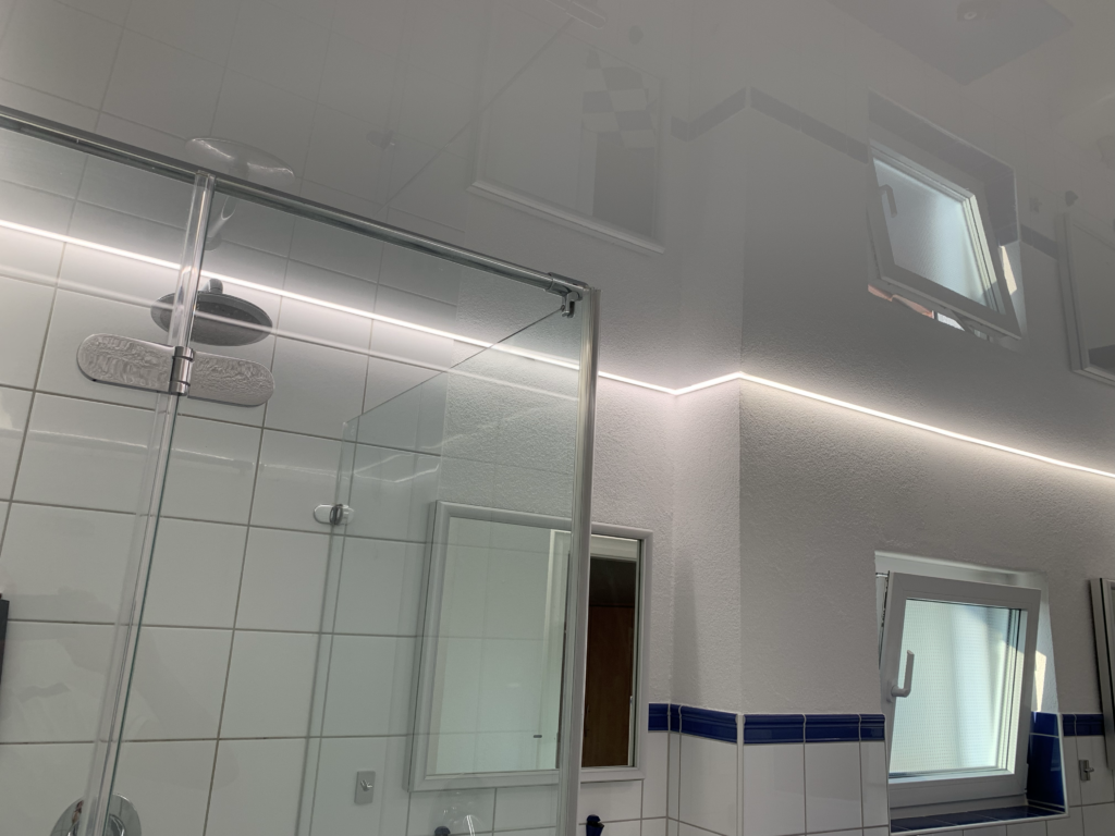 4_Lackspanndecke_weiß_Bad_LED_Beleuchtung_Trebur Weiße Lackspanndecke mit neutralweißer LED-Beleuchtung in der Schattenfuge in einem Bad