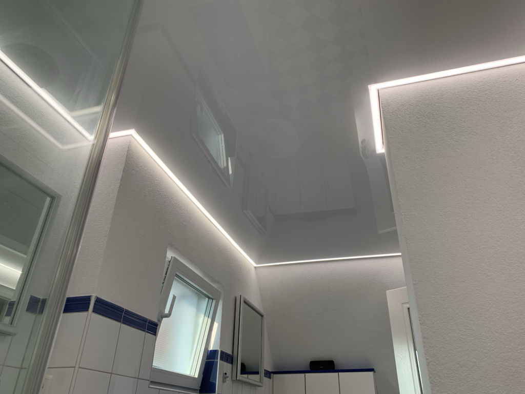 Weiße Lackspanndecke mit neutralweißer LED-Beleuchtung in der Schattenfuge in einem Bad