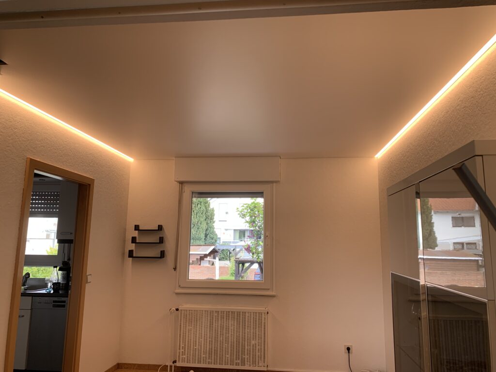 5_Satin_Spanndecke_Weiß_Indirekte_Beleuchtung_Warnweiß_Trebur Weiße Satin Spanndecke mit warmweißer LED-Beleuchtung auf zwei Seiten in einem Esszimmer