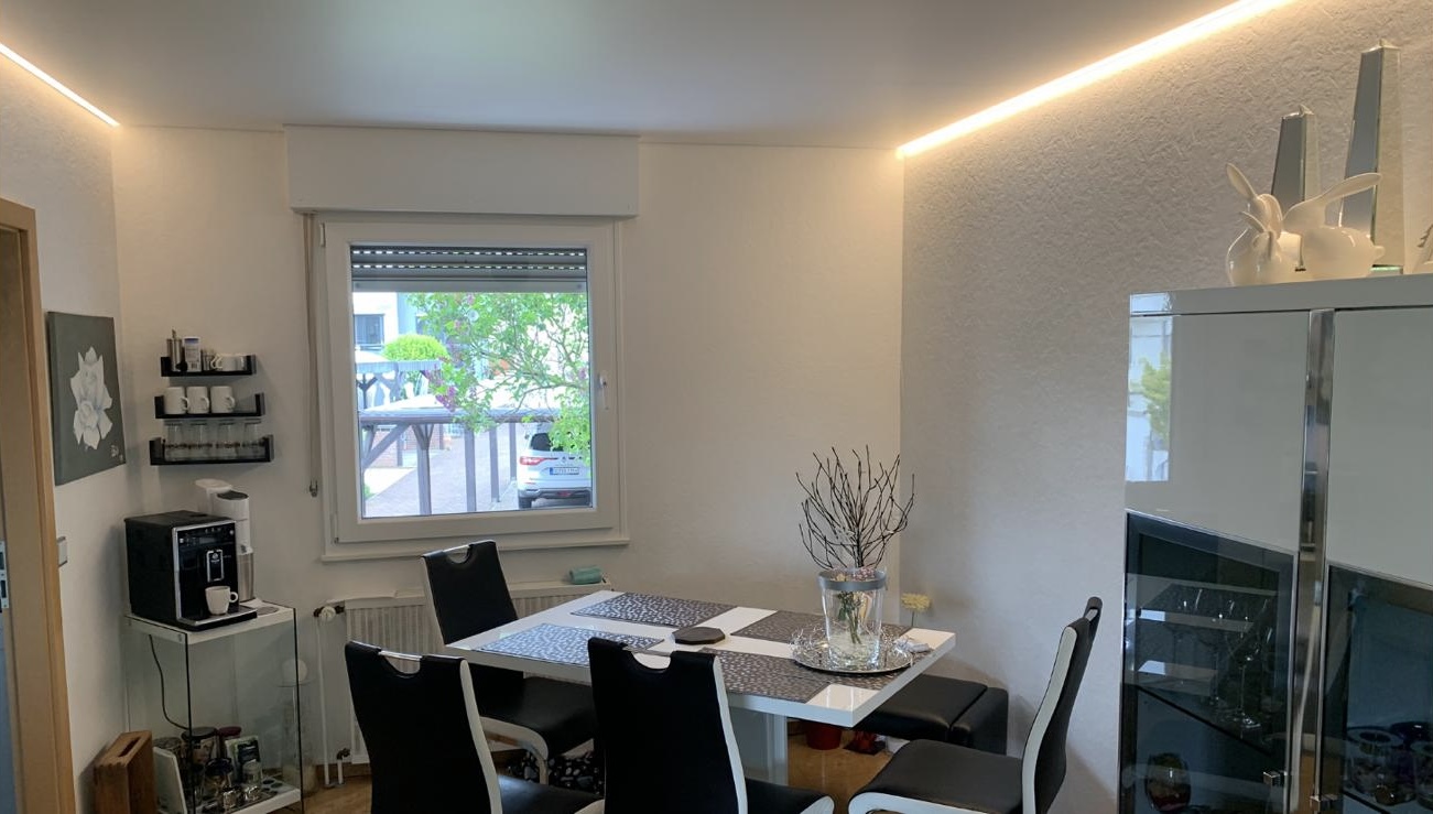 Weiße Satin Spanndecke mit warmweißer LED-Beleuchtung auf zwei Seiten in einem Esszimmer