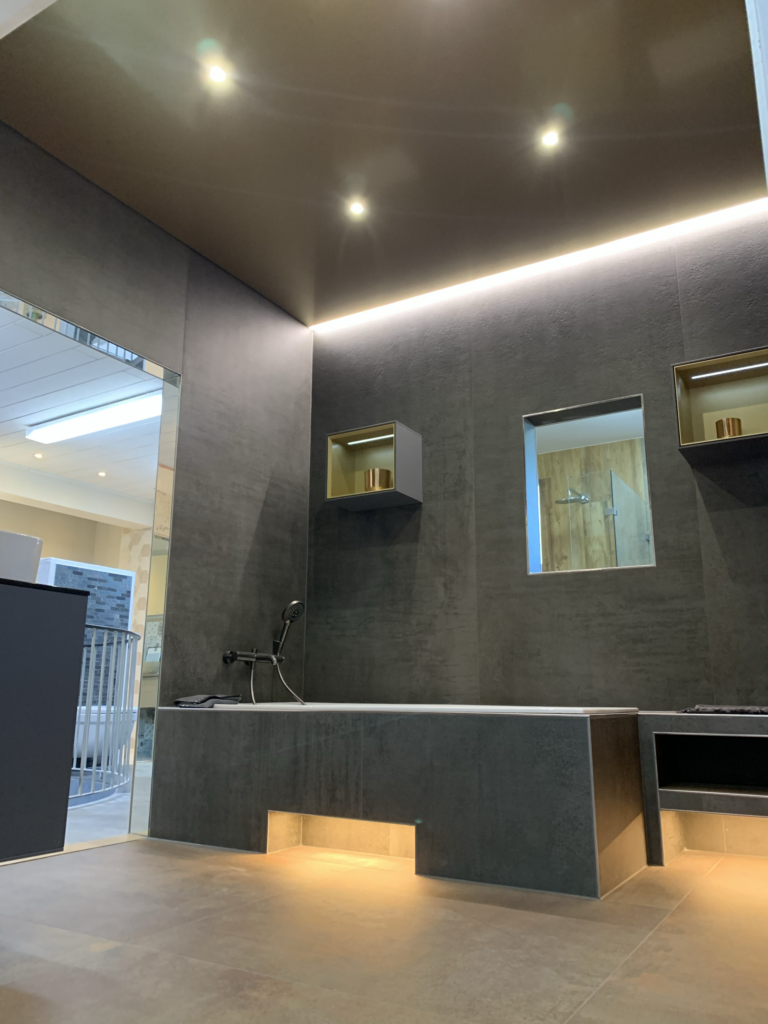 6_Spanndecke_Gold_metallic_LED-Beleuchtung_Schattenfuge_LED_Einbaustrahler_Darmstadt Spanndecke in Gold Metallic mit warmweißer LED-Beleuchtung in der Schattenfuge und LED Einbaustrahler in einer Fliesenausstellung in Darmstadt