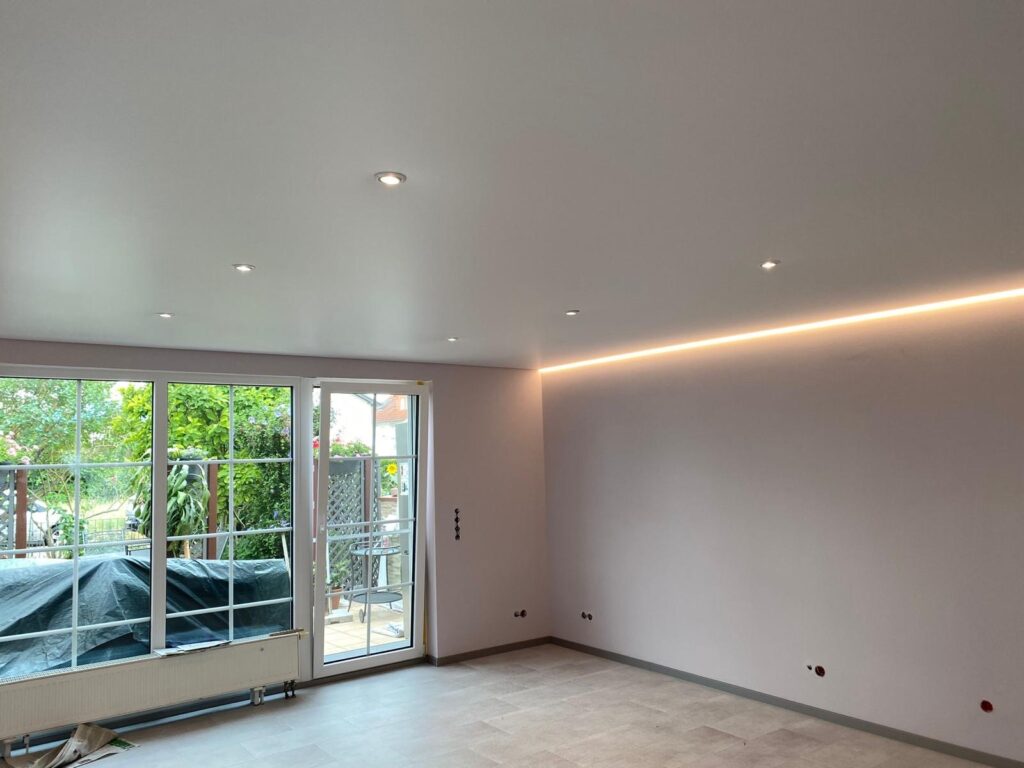 Satin Spanndecke in einem Wohnzimmer mit LED Einbaustrahler und LED-Beleuchtung in der Schattenfuge.