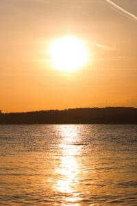 Peaceful sunset with glowing orange sky reflecting on tranquil ocean waters.