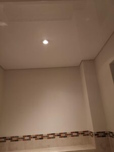 Weiße Lackspanndecke mit einem LED-Einbaustrahler montiert in einem Gästebad in Trebur.