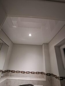 Weiße Lackspanndecke mit einem LED-Einbaustrahler montiert in einem Gästebad in Trebur.