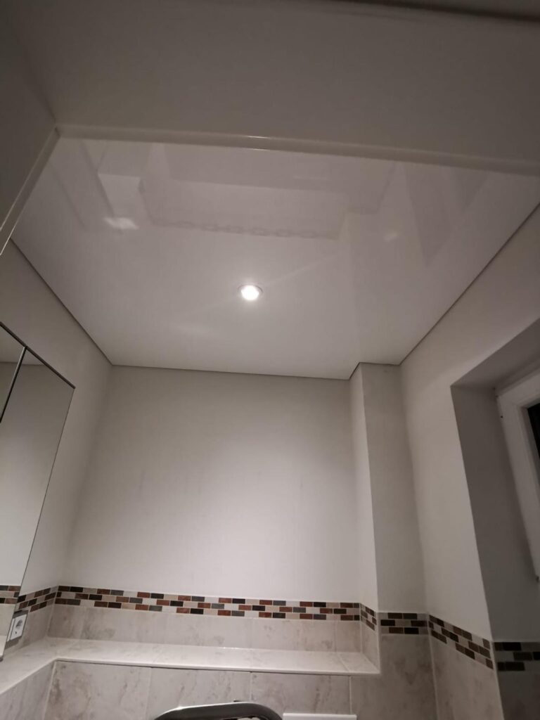 Weiße Lackspanndecke mit einem LED-Einbaustrahler montiert in einem Gästebad in Trebur.