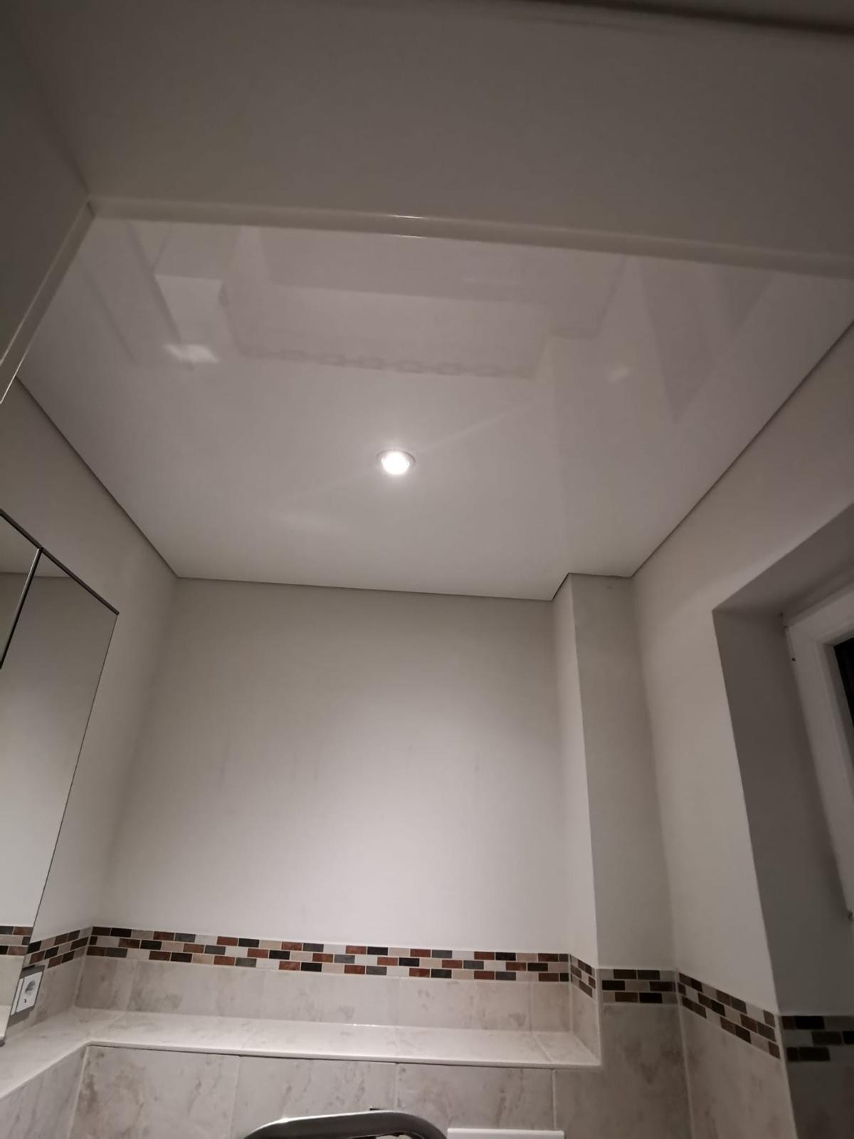 Weiße Lackspanndecke mit einem LED-Einbaustrahler montiert in einem Gästebad in Trebur.