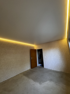 Zweite Raumansicht der weißen Spanndecke mit warmweiß beleuchteter Schattenfuge entlang zweier Wände.